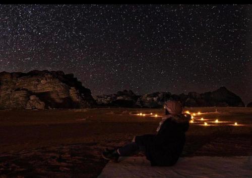 a person sitting on the ground looking up at the stars at Desert Bedouin adventure in Wadi Rum