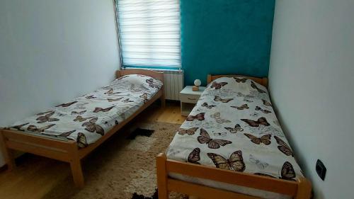 two beds in a room with butterflies on the sheets at Kuća za odmor Pale - Jahorina in Pale