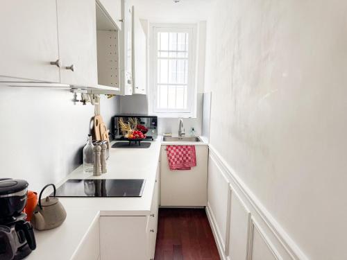 une cuisine blanche avec des armoires blanches et un évier dans l'établissement PenBed-2BR- Lovely parisian apt near Bastille, à Paris
