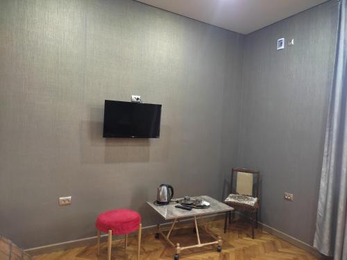 um quarto com uma mesa e uma televisão na parede em MariElla em Akhaltsikhe