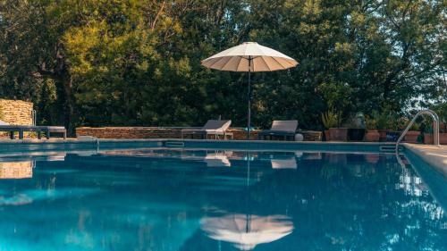 - une piscine avec un parasol, deux chaises et une table dans l'établissement Villa avec piscine privée sur jardin clos de 3000m2, à Grimaud