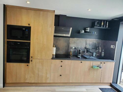 a kitchen with wooden cabinets and a microwave at appartement cosy in Feigères