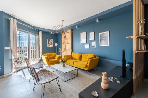 a living room with a yellow couch and blue walls at Luxury Mind Vue Exceptionnelle Pied dans l'eau Parkings privés 2 places Climatisation Hyper centre logement d'exception in La Grande-Motte