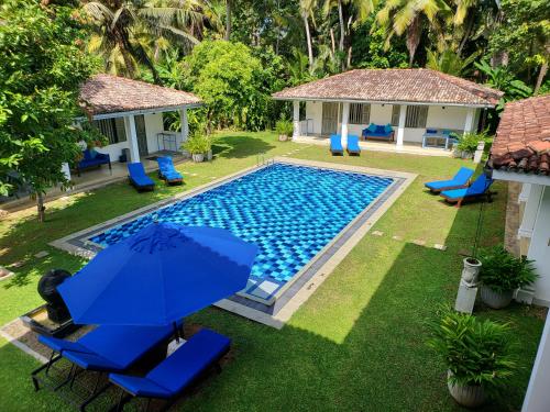 an overhead view of a pool with chairs and an umbrella at Thalpe Bungalows in Unawatuna