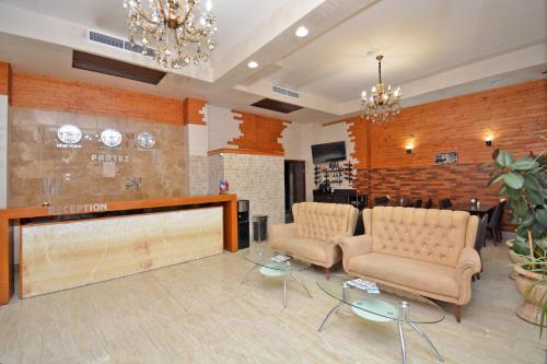 un vestíbulo con 2 sillas, una mesa y un bar en Partez Hotel en Ereván