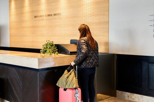 a woman standing at a counter with a suitcase at Miyajima Coral Hotel in Miyajima