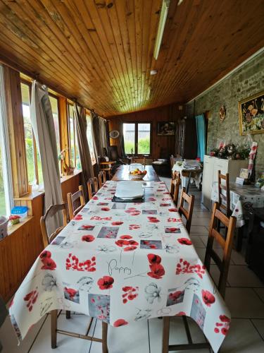 une salle à manger avec une longue table avec des roses rouges dessus dans l'établissement Chambres Les Salles, à Beauvoir