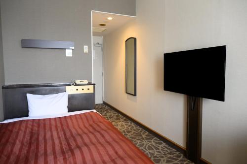 a hotel room with a bed and a flat screen tv at Miyajima Coral Hotel in Miyajima