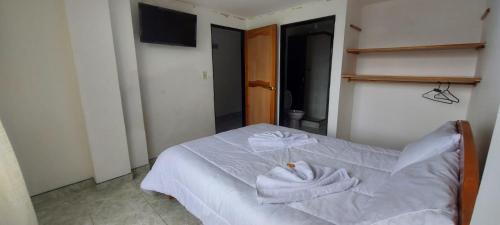 a bedroom with a white bed with towels on it at hotel S & C in Sogamoso