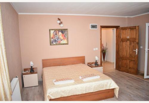 a bedroom with a bed and two tables and a door at Family Hotel Miglena in Govedartsi
