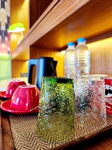 two green glasses sitting on a table with water bottles at Senglao Boutique Hotel Luang Prabang in Luang Prabang