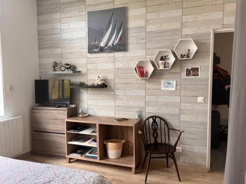 Cette chambre comprend un bureau, une télévision et un mur. dans l'établissement Le calme de la campagne dans le Vexin, à Santeuil