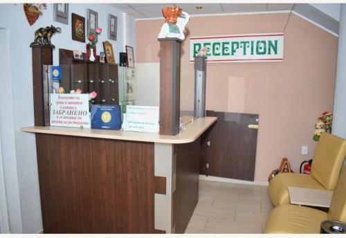a reception desk in a waiting room with a sign at Family Hotel Miglena in Govedartsi