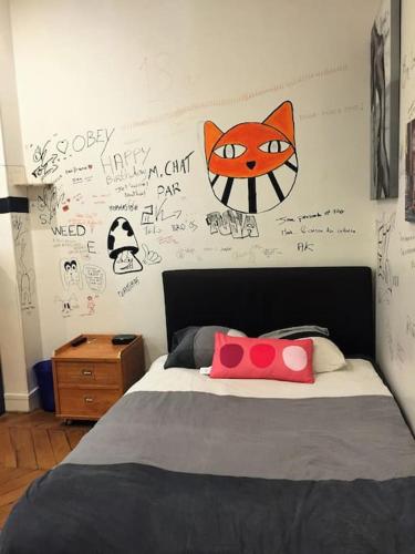 une chambre avec un lit avec un visage de chat sur le mur dans l'établissement 5 minutes Village Olympique Tour Eiffel, à Paris