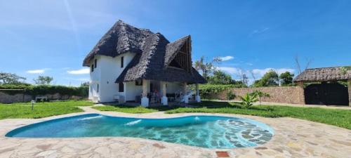 Casa con techo de paja y piscina en Nyuso za Afrika en Watamu