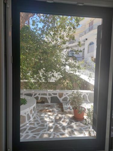 una finestra con vista su un patio con tavolo e albero di Mesa Vrisi a Karpathos
