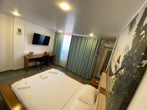 a room with a bed and a desk and a tv at Hotel Rupa Rupa in Tingo María
