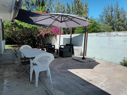 un patio avec une table, des chaises et un parasol dans l'établissement Villa SoKool, à Saint-Paul