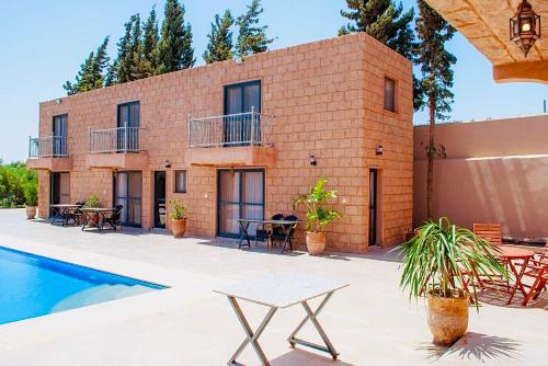 une maison en briques avec une piscine en face de celle-ci dans l'établissement Villa Vert, à Essaouira