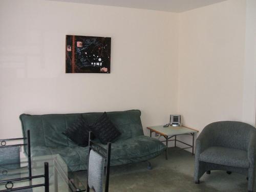 a living room with a green couch and a chair at Pavilion Motel & Conference Centre in Palmerston North