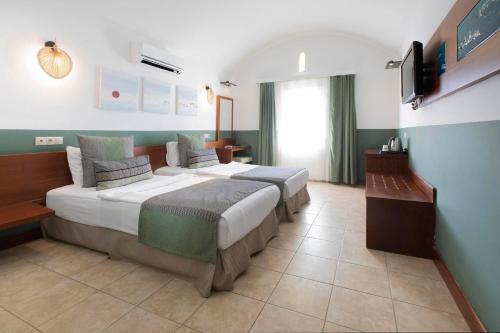 Habitación de hotel con 2 camas y TV en Manastir Hotel & Suites, en Bodrum City