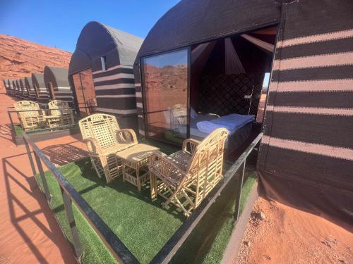 a group of wicker chairs and a bed on the back of a house at Desert Bedouin adventure in Wadi Rum