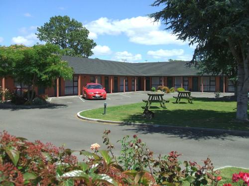 a red car is parked in front of a building at Pavilion Motel & Conference Centre in Palmerston North