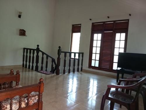 sala de estar con escaleras, ventanas y piano en Prasanna Homes, en Matara