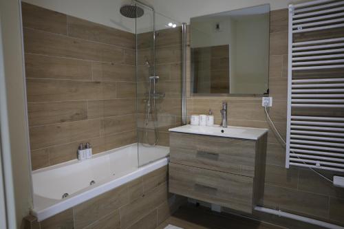 La salle de bains est pourvue d'une baignoire, d'un lavabo et d'une douche. dans l'établissement Cosy T3 Oiseau de Paradis Billard Balnéothérapie proche aéroport et centre-ville, à Saint-Denis