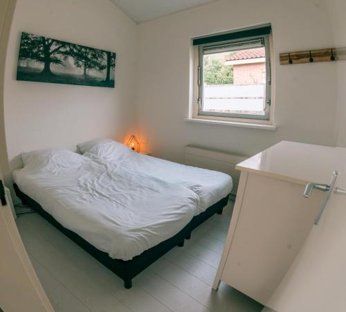 a small bed in a room with a window at Rekerlanden 275 in Warmenhuizen