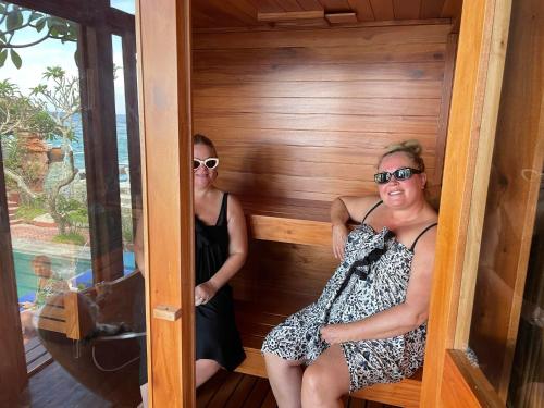 two women sitting in a sauna at a resort at Puri Oka Beach Bungalows in Candidasa