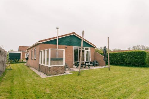 a small brick house with a green roof at Rekerlanden 275 in Warmenhuizen