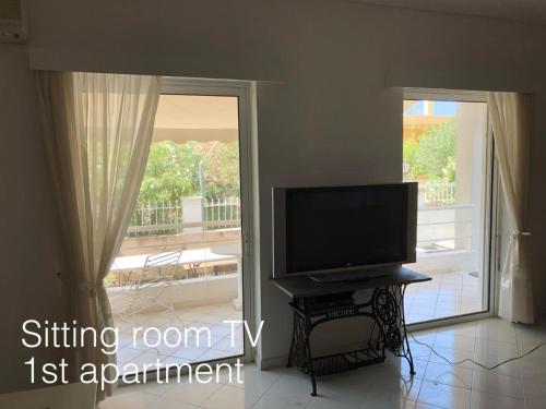 a living room with a television and a sliding glass door at Gnick Apartments in Lagonissi