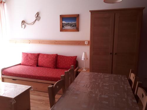 un salon avec un canapé rouge et une table dans l'établissement Résidence de Tourisme La Meije Blanche, à Villar-dʼArêne