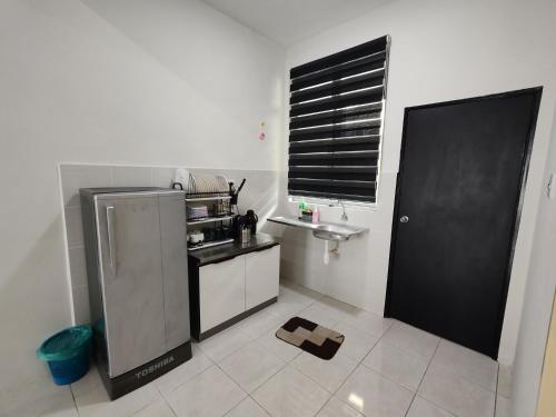 a small kitchen with a sink and a refrigerator at Suria Villa @ 5 mins A'famosa Resort in Kampong Alor Gajah