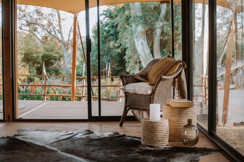 a wicker chair sitting in a room with a porch at Worlds Apart - River Front Guest Farm & Camping in Bonnievale