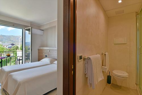 a hotel room with two beds and a balcony at Hotel & Apartments Villa Linda in Giardini Naxos