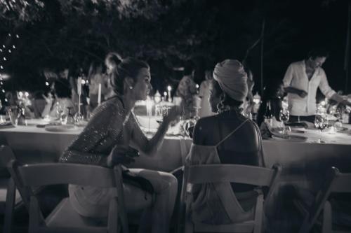 two women sitting in chairs at a table at a party at Worlds Apart - River Front Guest Farm & Camping in Bonnievale