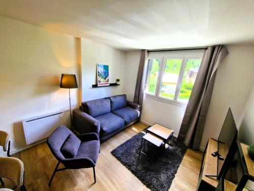 un salon avec un canapé bleu et une fenêtre dans l'établissement Appart Les Cosmiques, Vue Mont Blanc - Aiguille du Midi, à Chamonix-Mont-Blanc