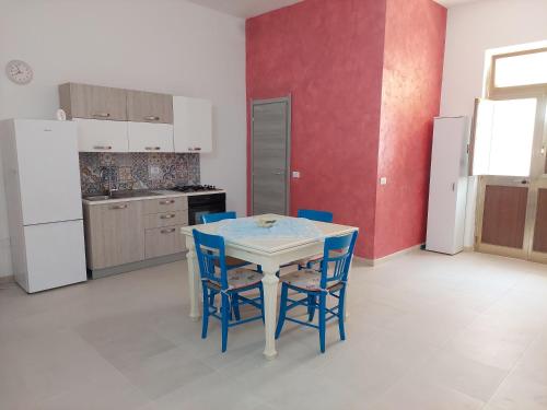 eine Küche mit einem weißen Tisch und blauen Stühlen in der Unterkunft Casa Rizza in Portopalo