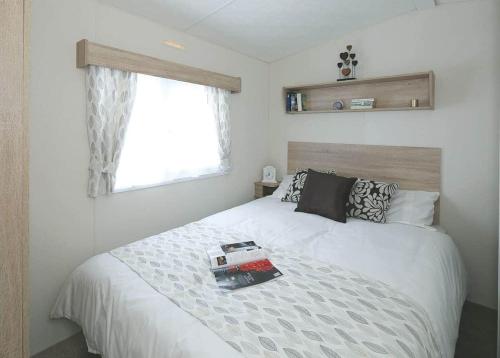 um quarto com uma cama com um livro em Burrowhead Holiday Village em Isle of Whithorn