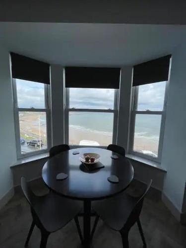 a table and chairs in a room with two windows at Superb 2 Bedroom Sea View Flat in Scarborough
