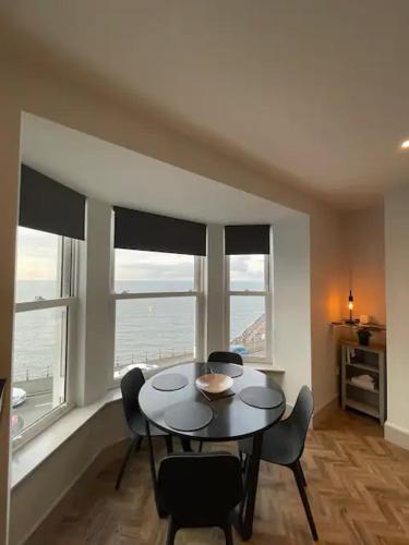 a dining room with a table and chairs and windows at Superb 2 Bedroom Sea View Flat in Scarborough