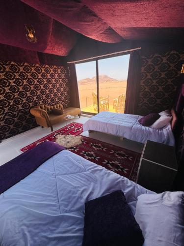 two beds in a room with a view of the desert at Desert Bedouin adventure in Wadi Rum