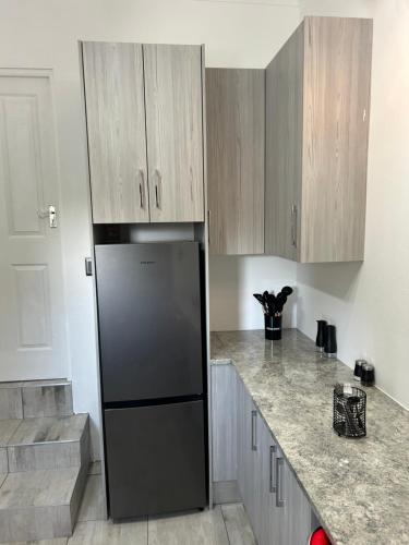 a kitchen with a black refrigerator and wooden cabinets at SiBella guest house in Bloemfontein