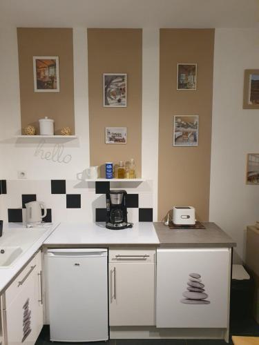 une cuisine avec des armoires blanches et du carrelage noir et blanc dans l'établissement Appartement quartier Teinturiers climatisé, à Avignon