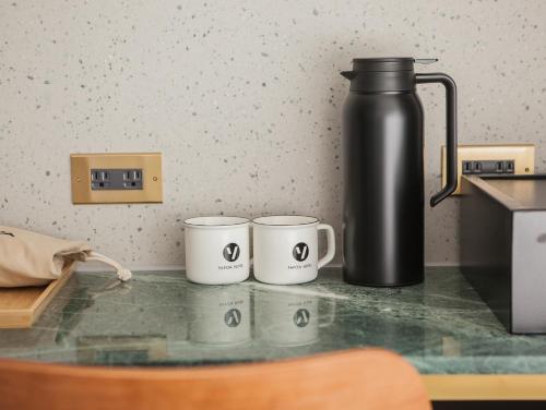 three coffee cups sitting on a counter with a thermos at PAPO'A Harbor Hotel in Kaohsiung