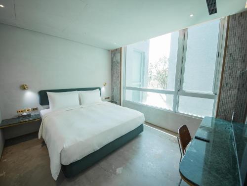 a bedroom with a white bed and a glass table at PAPO'A Harbor Hotel in Kaohsiung