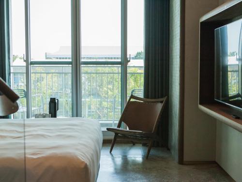a hotel room with a bed and a chair and a television at PAPO'A Harbor Hotel in Kaohsiung