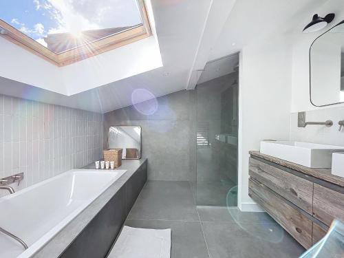 La salle de bains est pourvue d'une baignoire, d'un lavabo et d'une lucarne. dans l'établissement Makore - Les Gets - Centre village, aux Gets